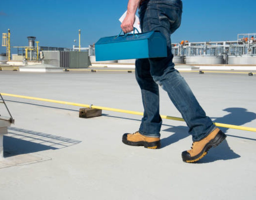 Commercial roofing crew in Hamilton, NJ examining drainage paths and flashing on a flat roof